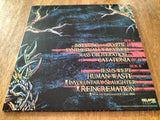 Vinyl record cover with text and artistic design on a wooden surface